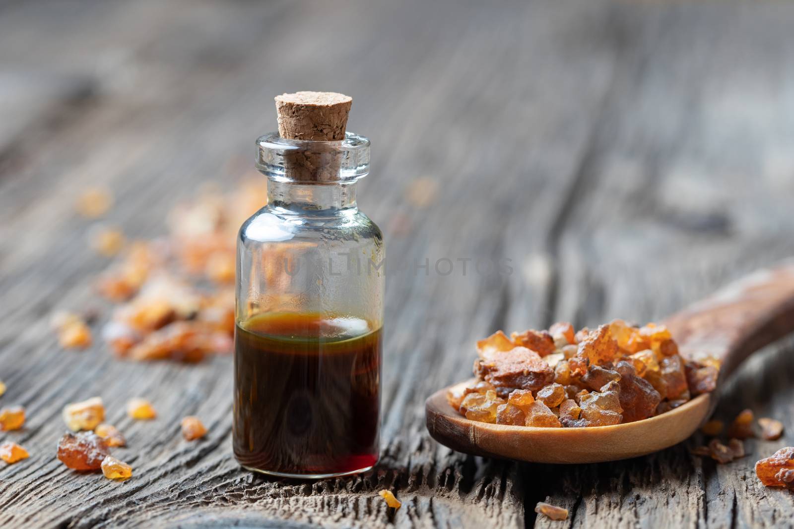 A bottle of essential oil with myrrh resin on a spoon