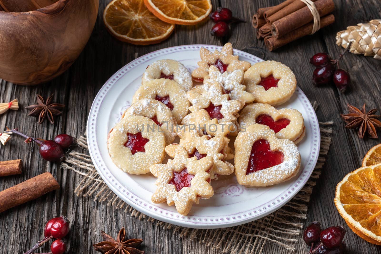 Traditional Linzer Christmas cookies filled with strawberry jam on a wooden table