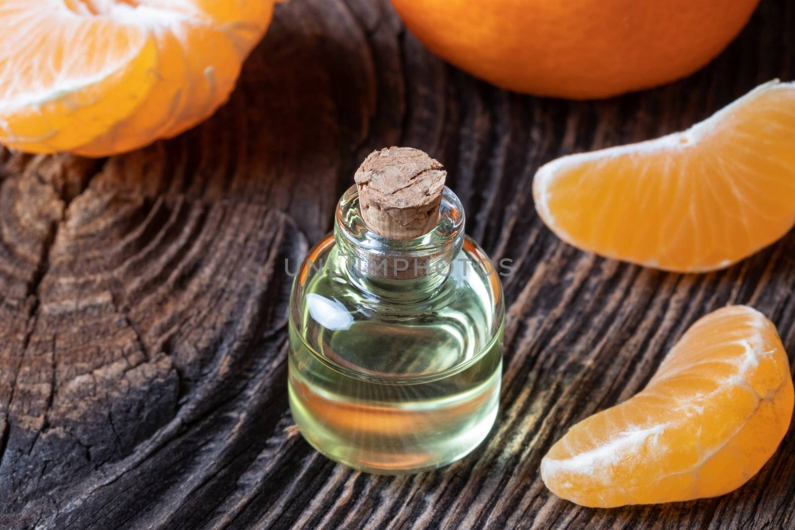 A bottle of citrus essential oil with fresh tangerines