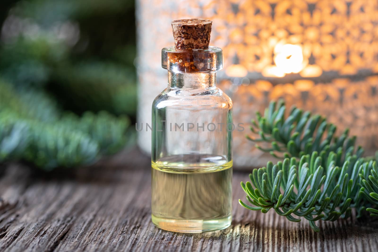 A bottle of essential oil with fresh fir branches