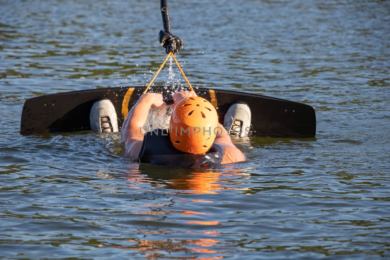 Wakeboarder holding rope and taking off from water