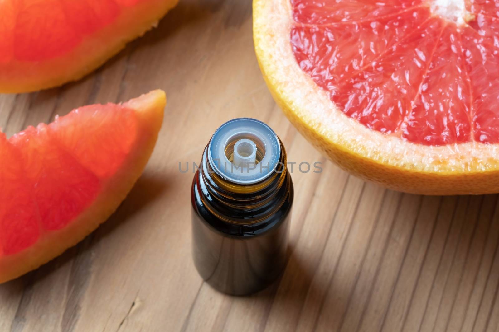 A bottle of citrus essential oil with fresh grapefruit