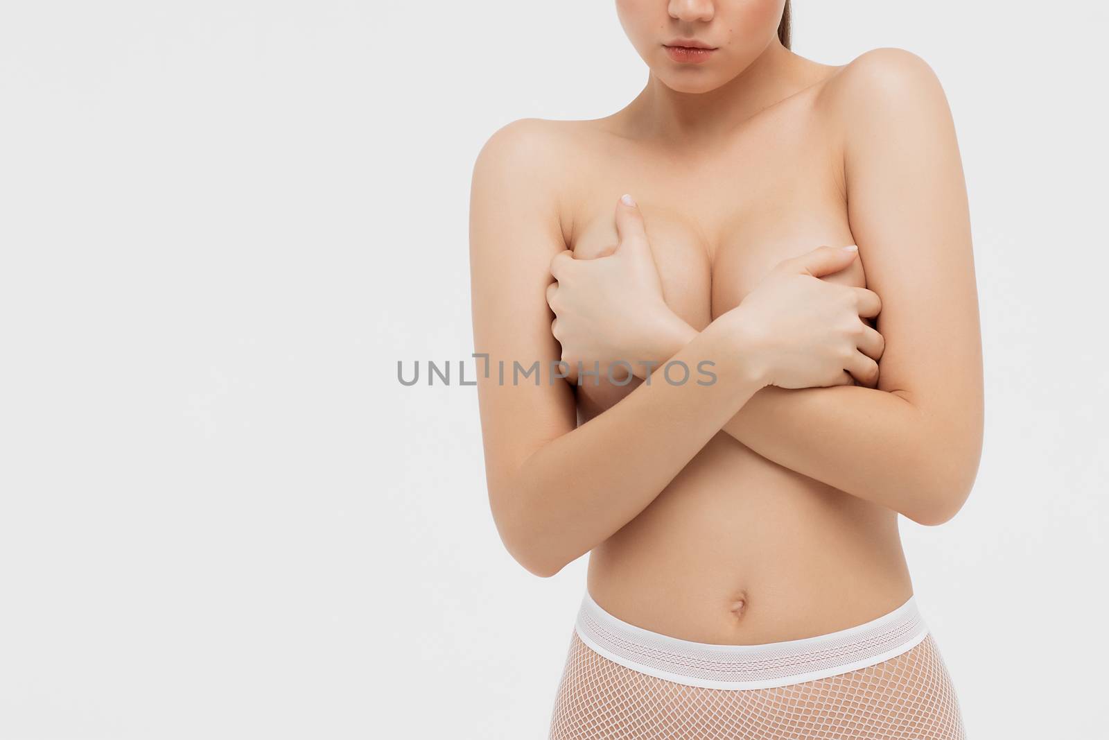 Beautiful slim woman covering her nude breast isolated on white background.