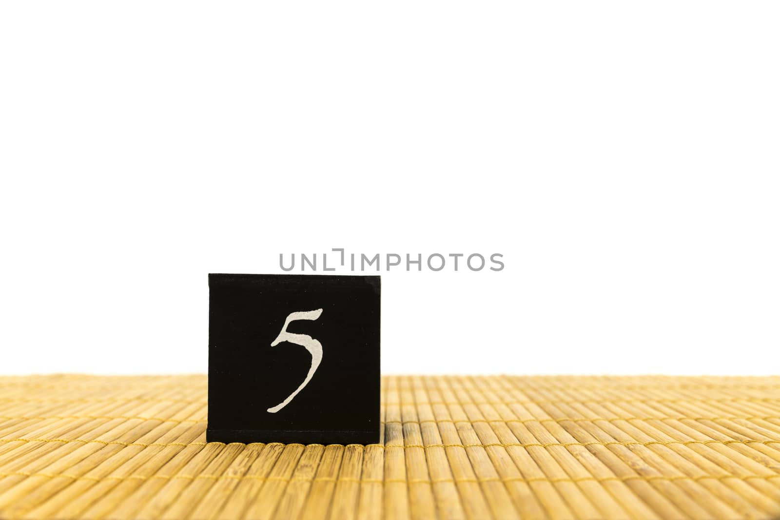 black number 5 block on bamboo underground and with isolated white background