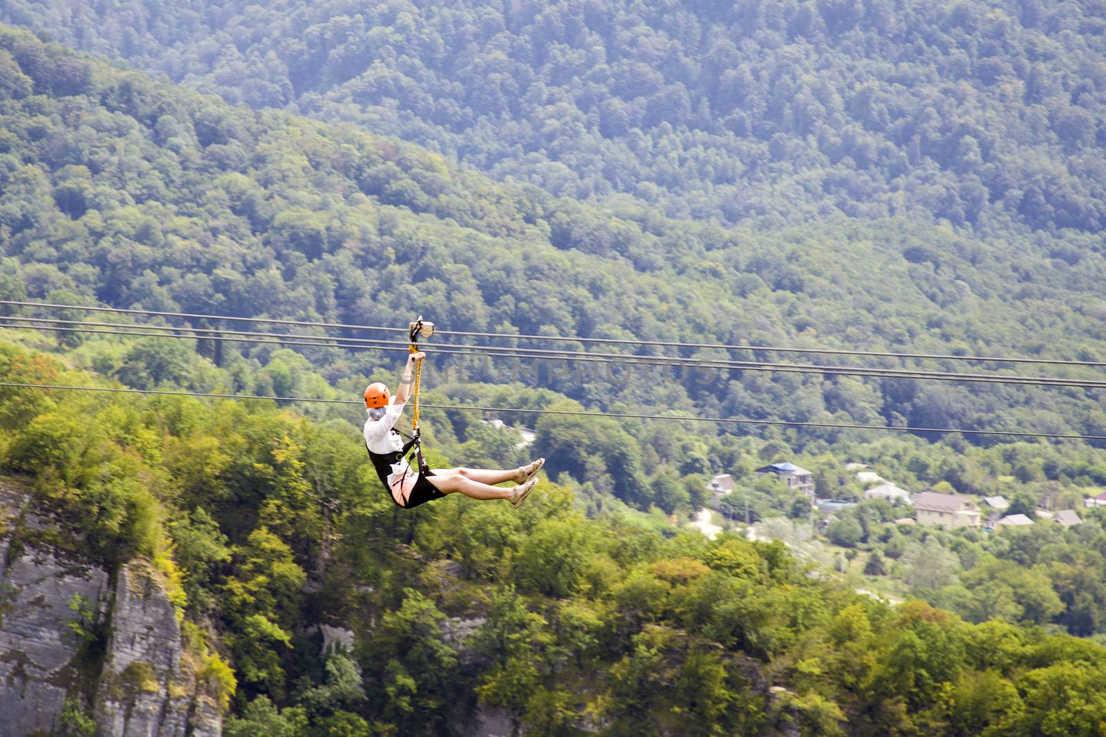 Man and woman hanging on a rope-way. Couple in helmets is riding on a cable car. Zipline is an exciting adventure activity.
