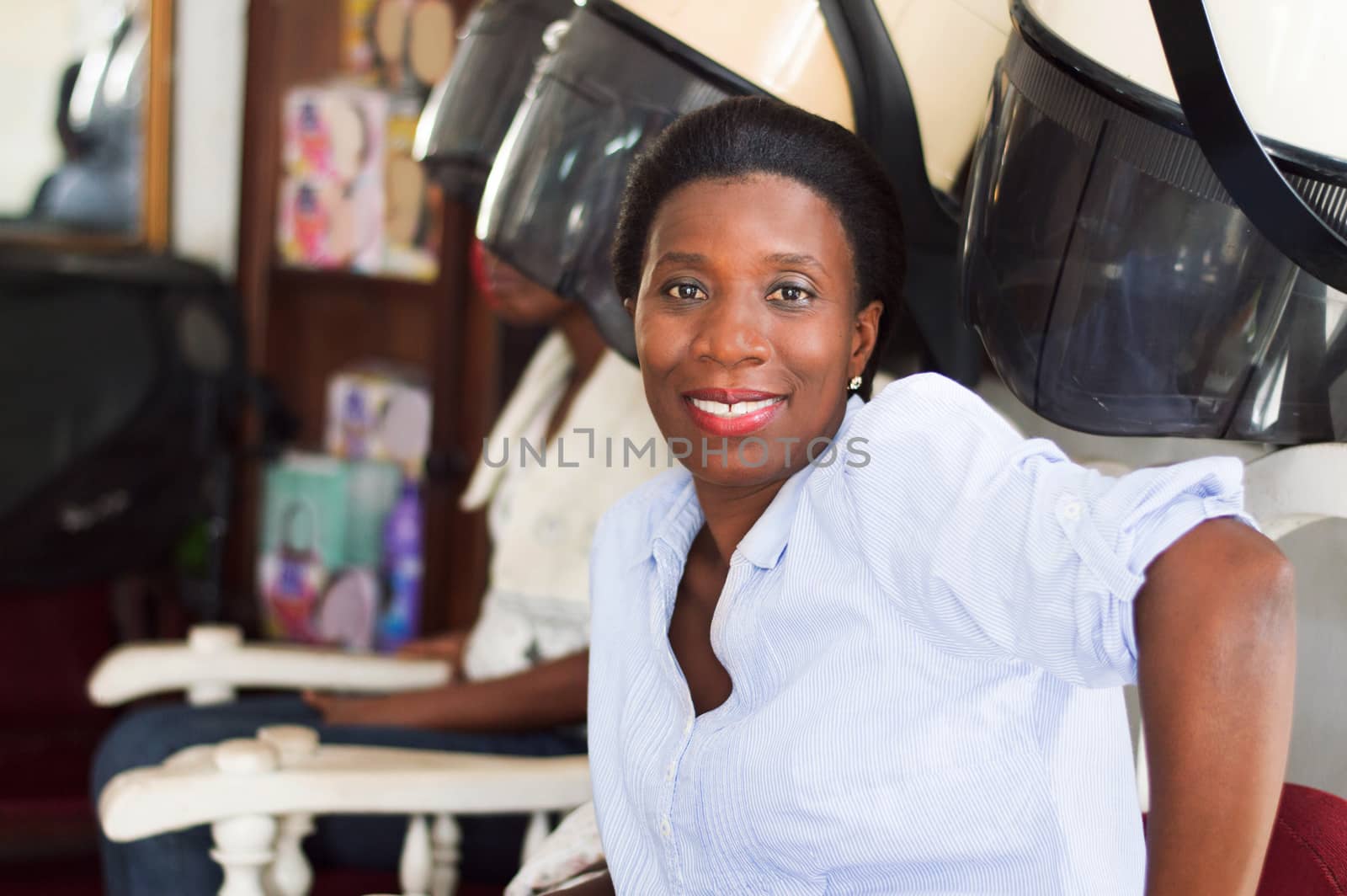 smiling young woman sitting at the hair salon looking in the camera.