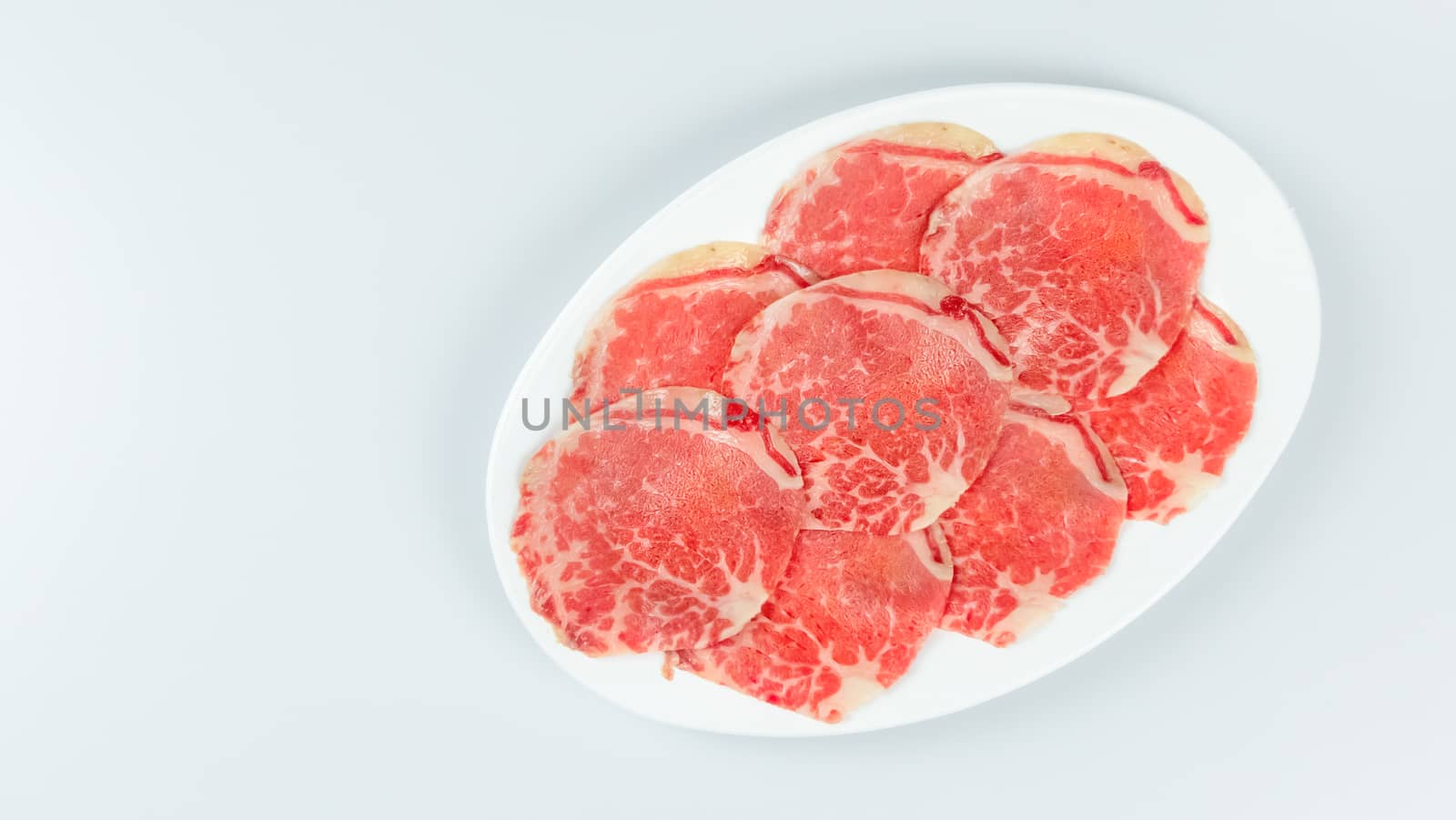 Top view of some raw beef on a plate over white background