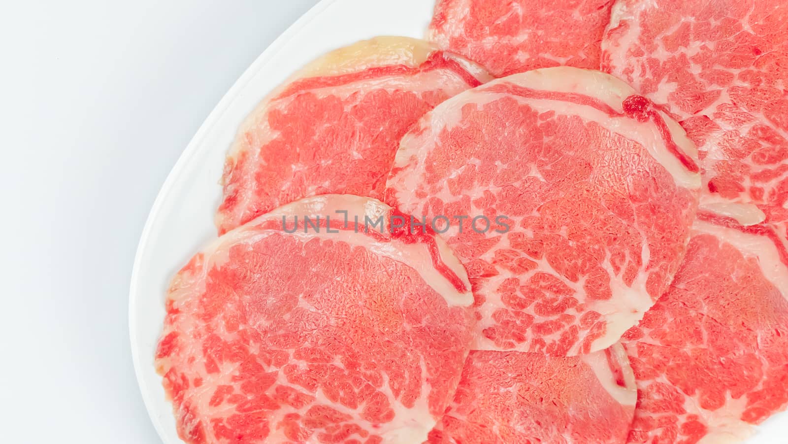 Top view of some raw beef on a plate over white background