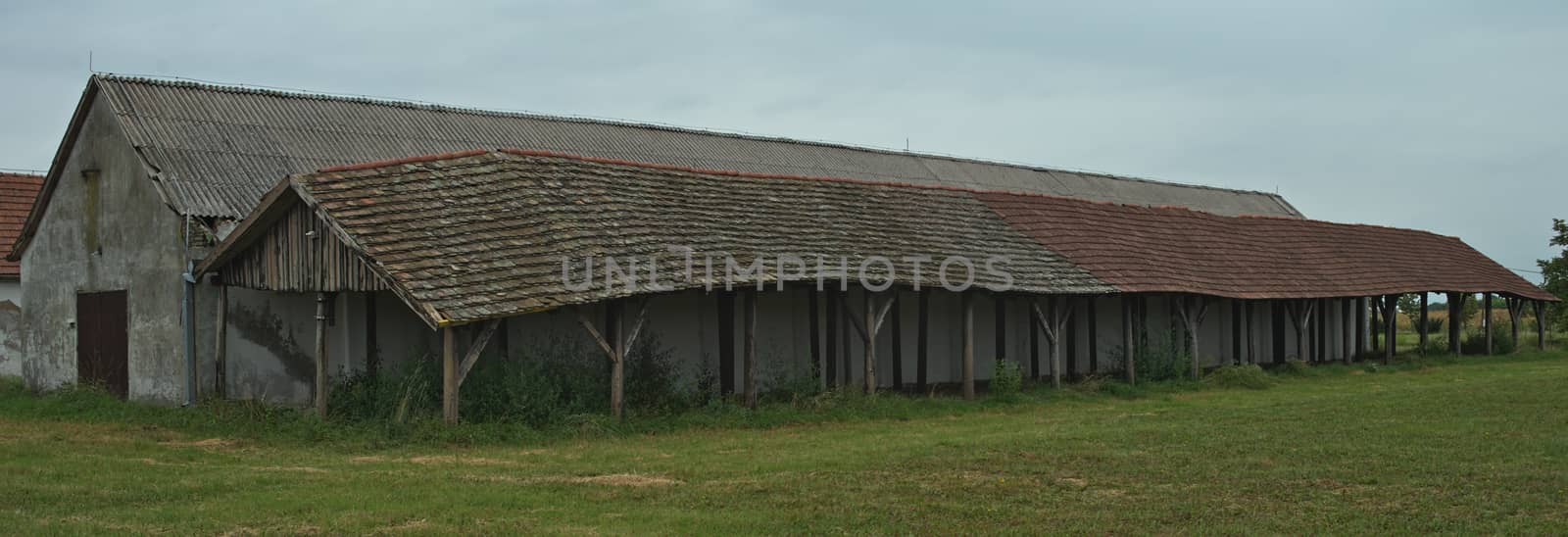 Long shed next to stable on a large field, side view