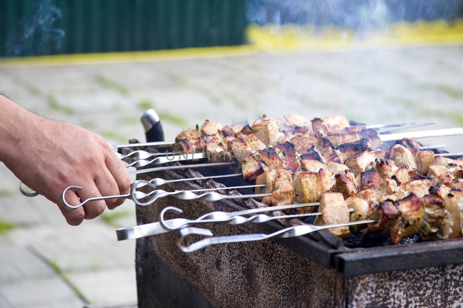 Grilled kebab cooking on metal skewer. Roasted meat cooked at barbecue. Traditional eastern dish, shish kebab. Grill on charcoal, picnic, street food