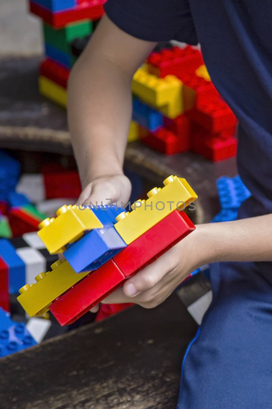 Closeup of child's hands with colorful plastic bricks and details of toys. Boy playing with parts of bright small spare parts of lego.