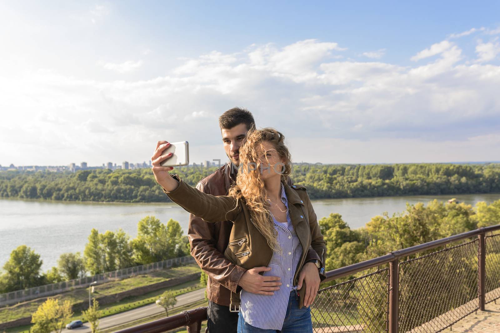 Modern couple taking a selfie photos close to river bank