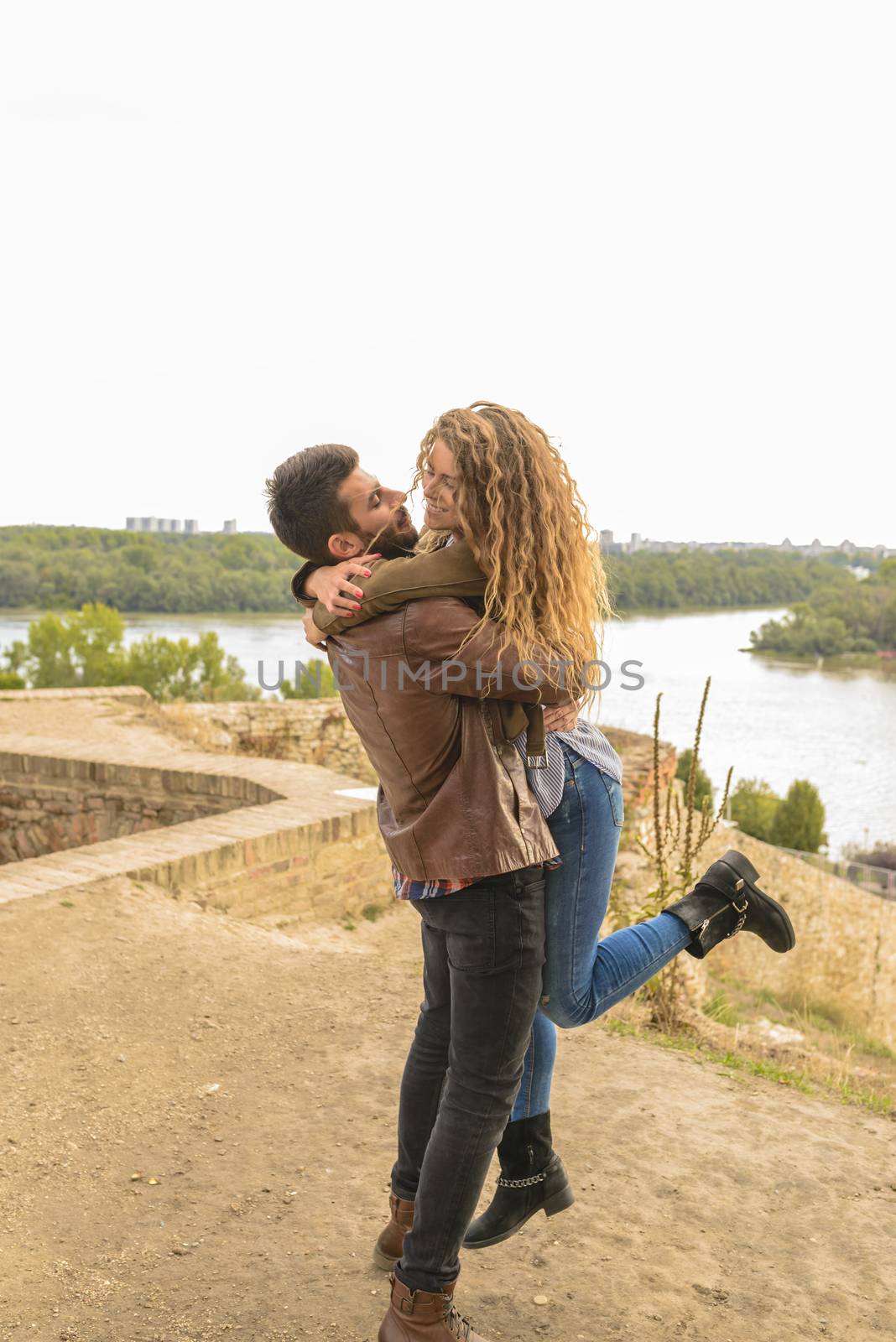 Happy attractive couple near the river bank by VeraAgency