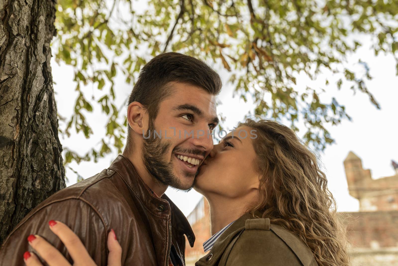 Attractive woman kissing her boyfriend in the public park