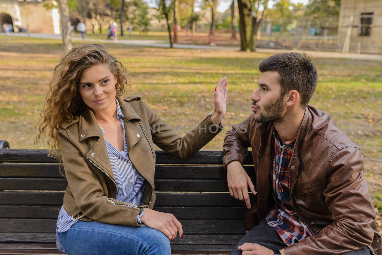 Young man and woman angry and conflicting on a park bench