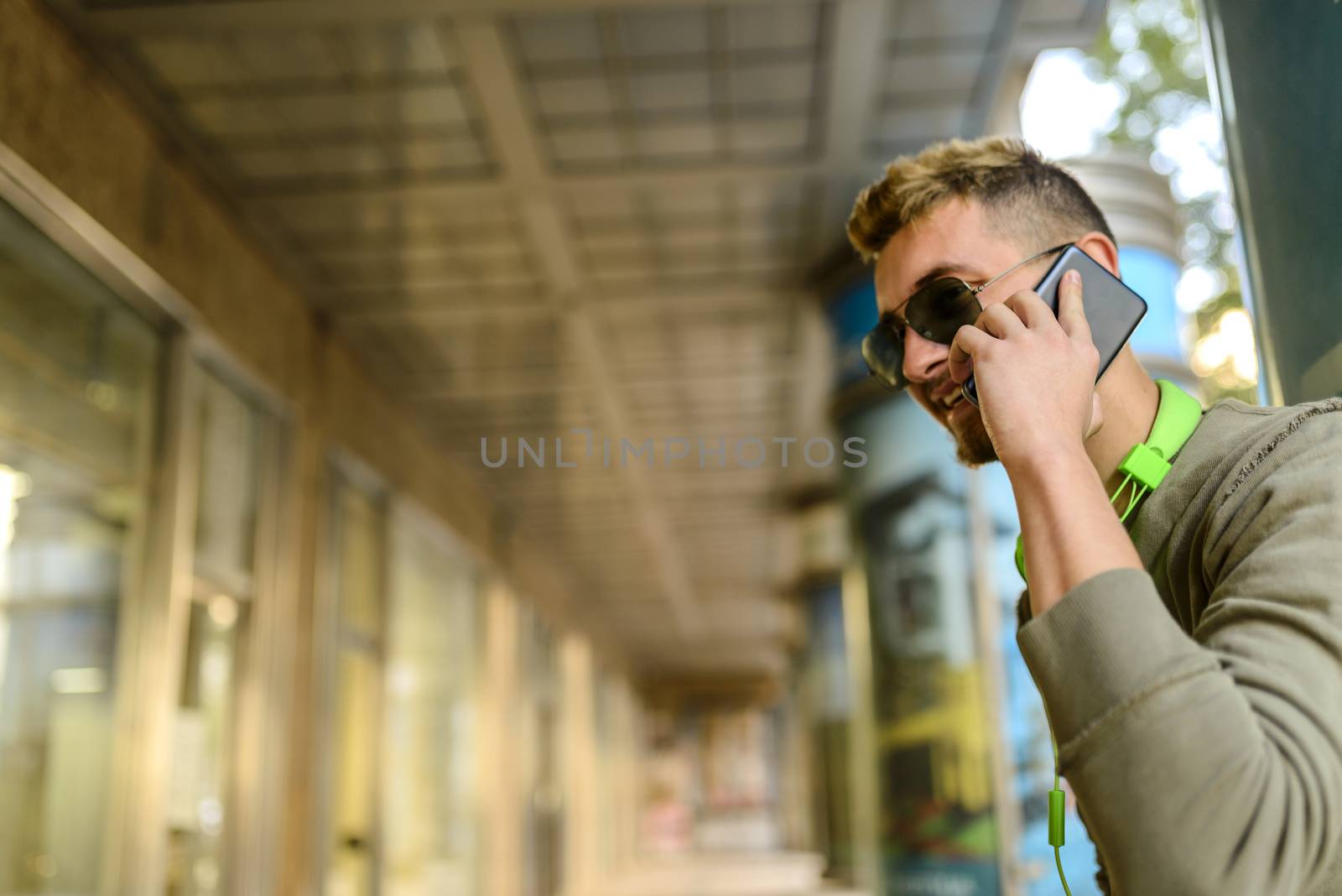 Handsome young man using his phone outdoors by VeraAgency