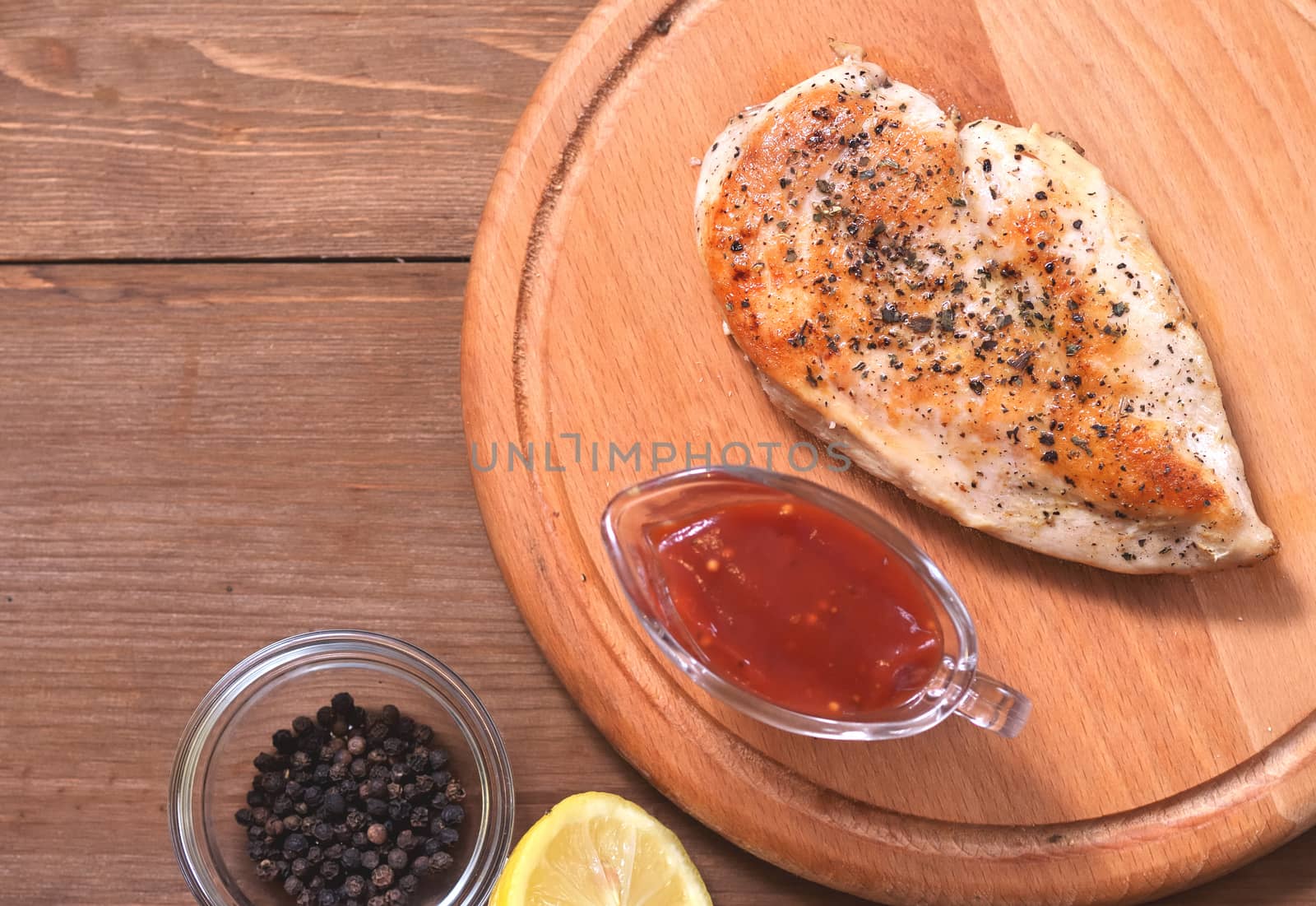 Fried chicken fillet in spices, next to a saucer, spices and lemon, top view