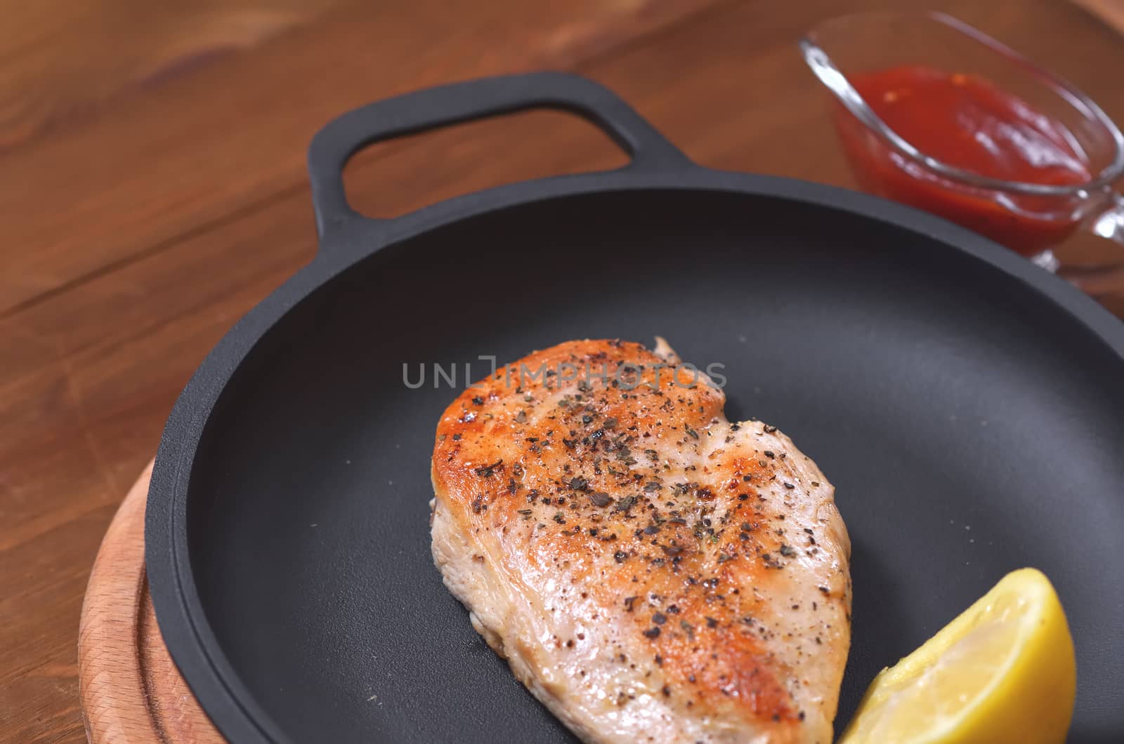 On a new frying pan, chicken fillet, fried with spices, lemon and sauce