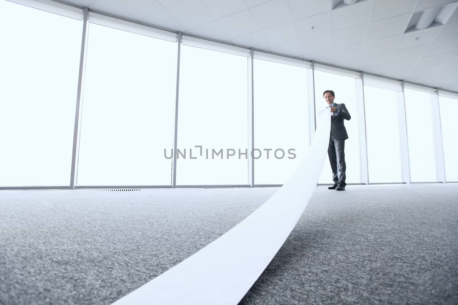 Businessman reading long paper list by ALotOfPeople