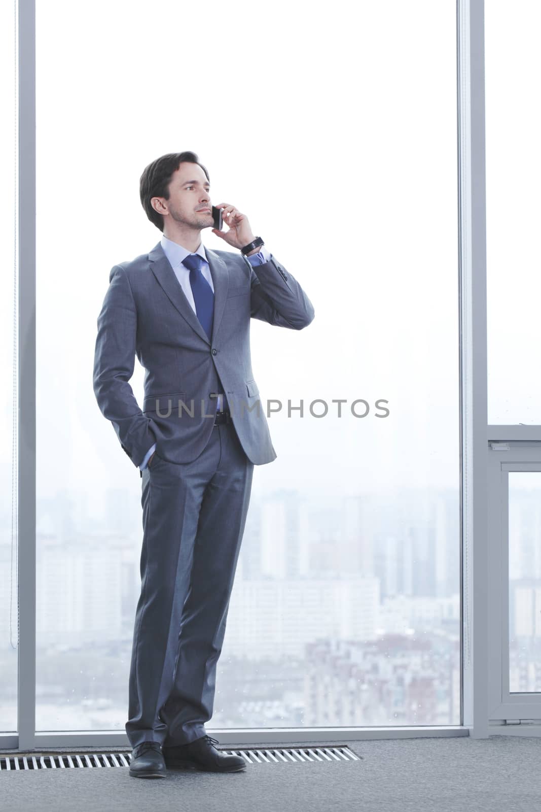 Portrait of a successful man, having a business conversation, at work station by the window