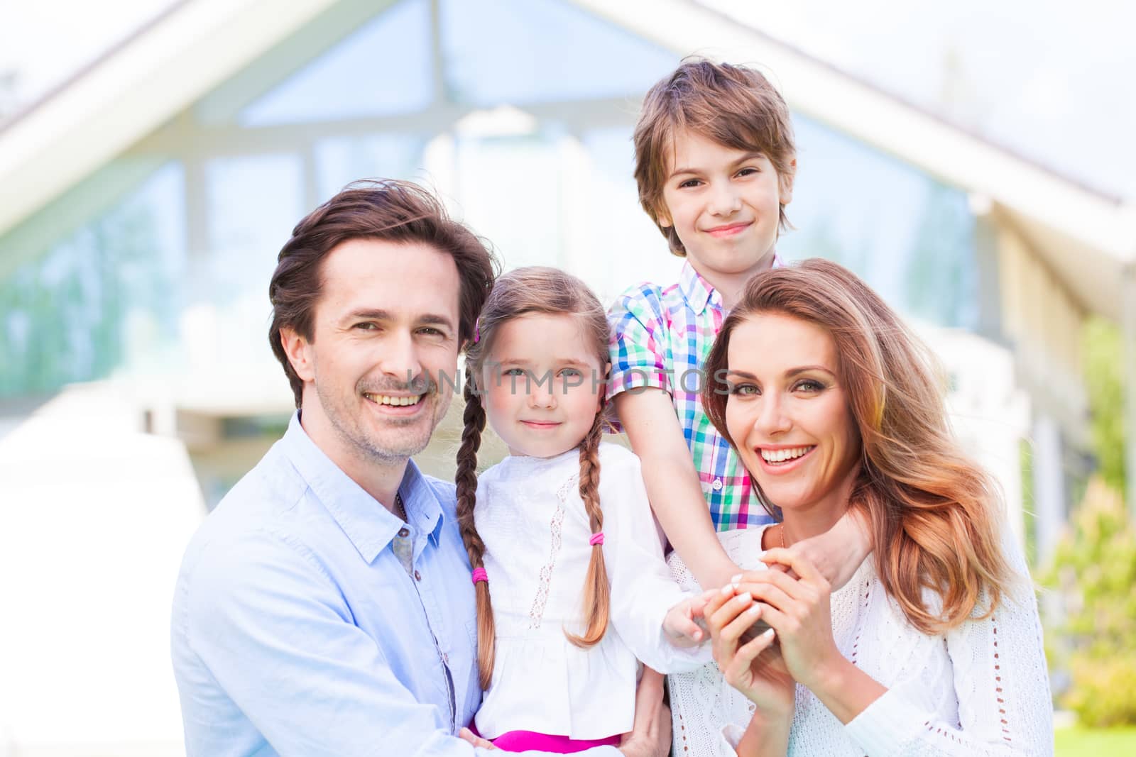Happy family of parents and children in front of their house outdoors