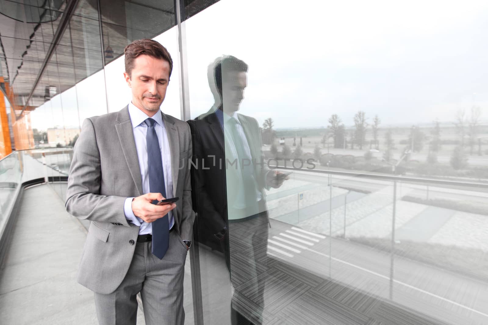 Businessman using smart phone at the balcony of office building