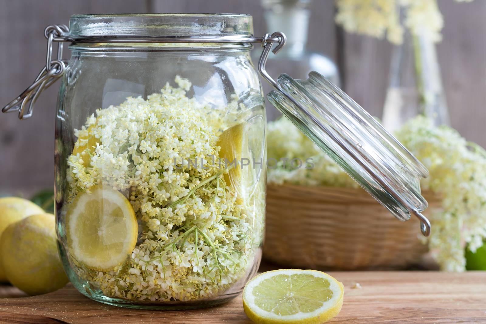 Fresh elder flowers and lemon in a glass jar, ready to prepare a natural elder flower syrup