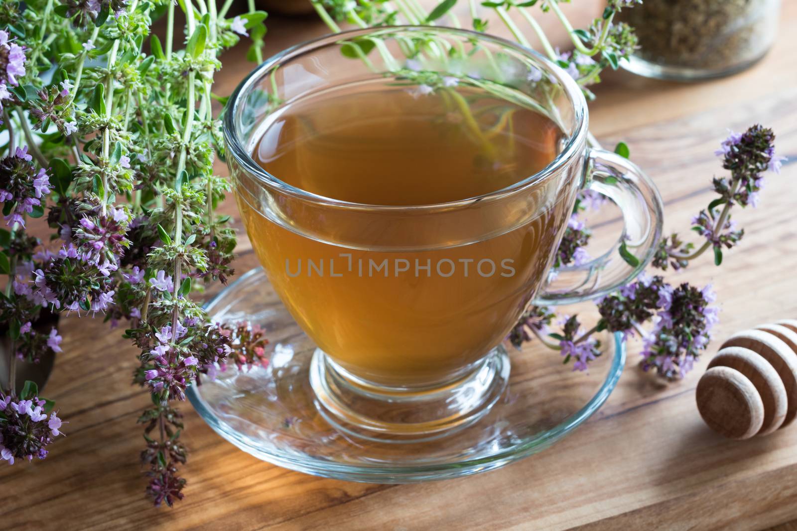 A cup of creeping thyme (thymus serpyllum) tea, with blooming creeping thyme twigs on a wooden background