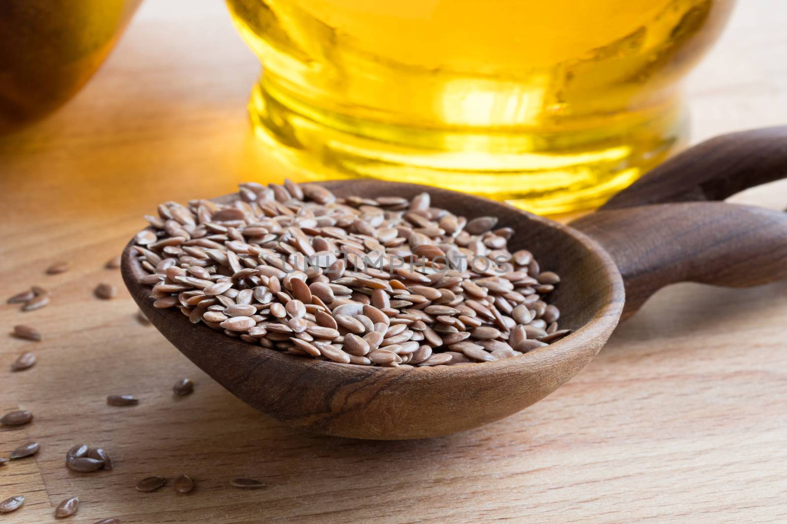 Linseed on a wooden spoon, with flax seed oil in the background