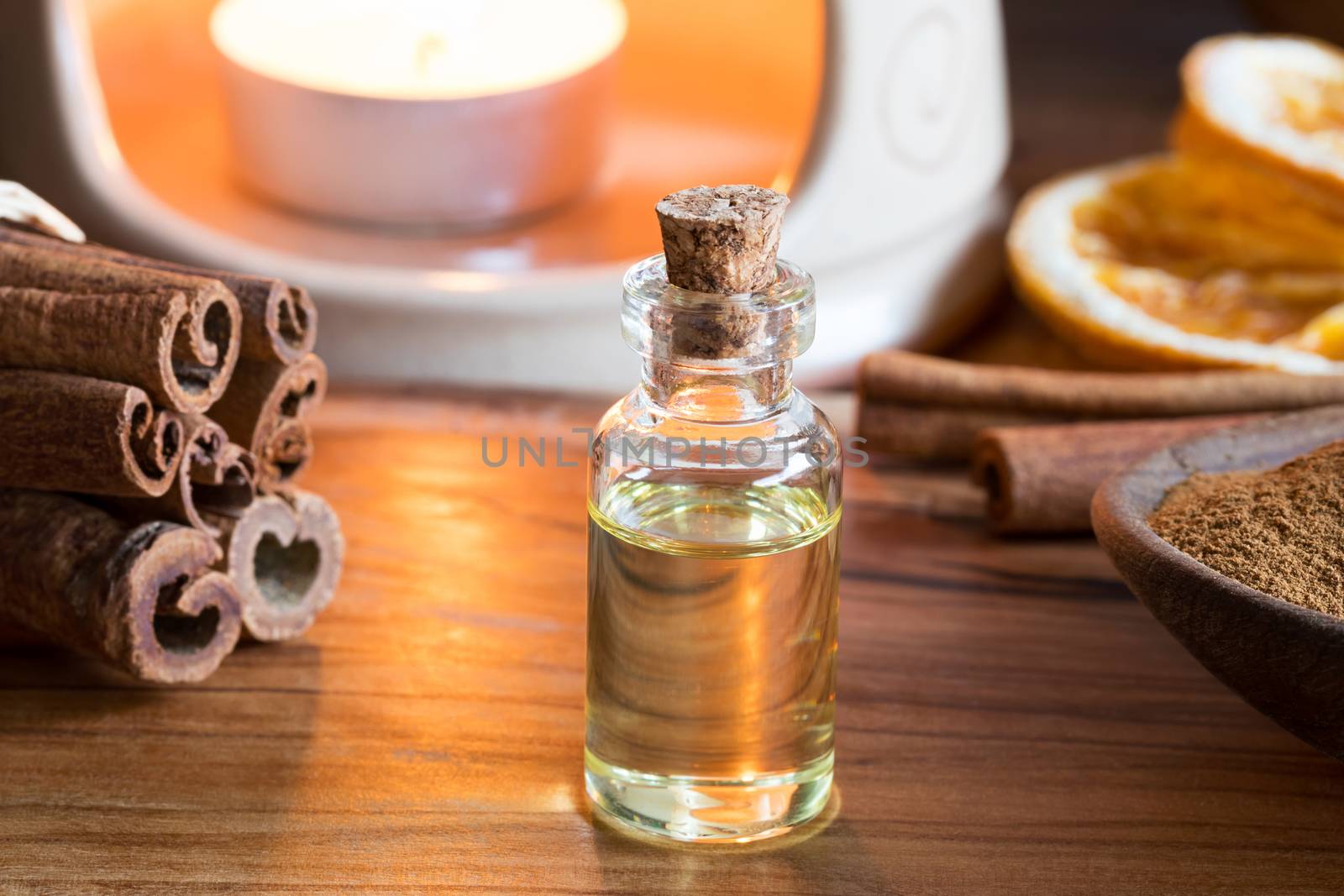 A bottle of cinnamon essential oil with cinnamon sticks and an aroma lamp
