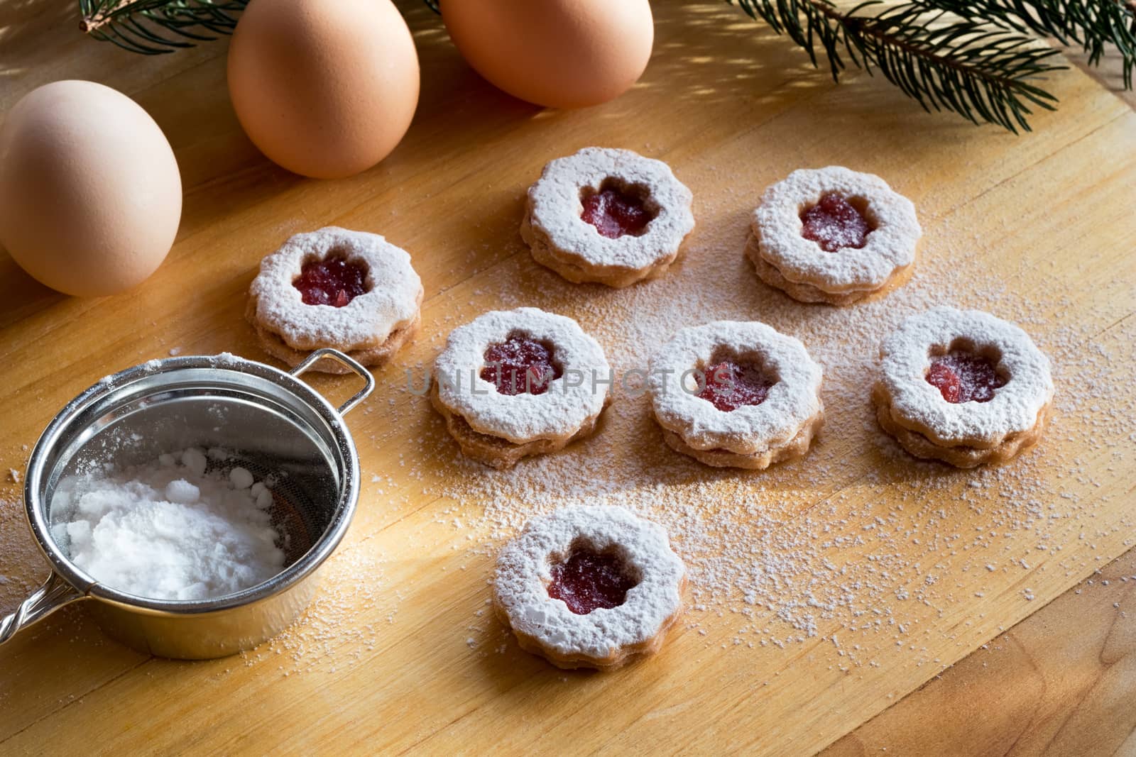 Trraditional Linzer Christmas cookies dusted with sugar, with a sifter and eggs in the background