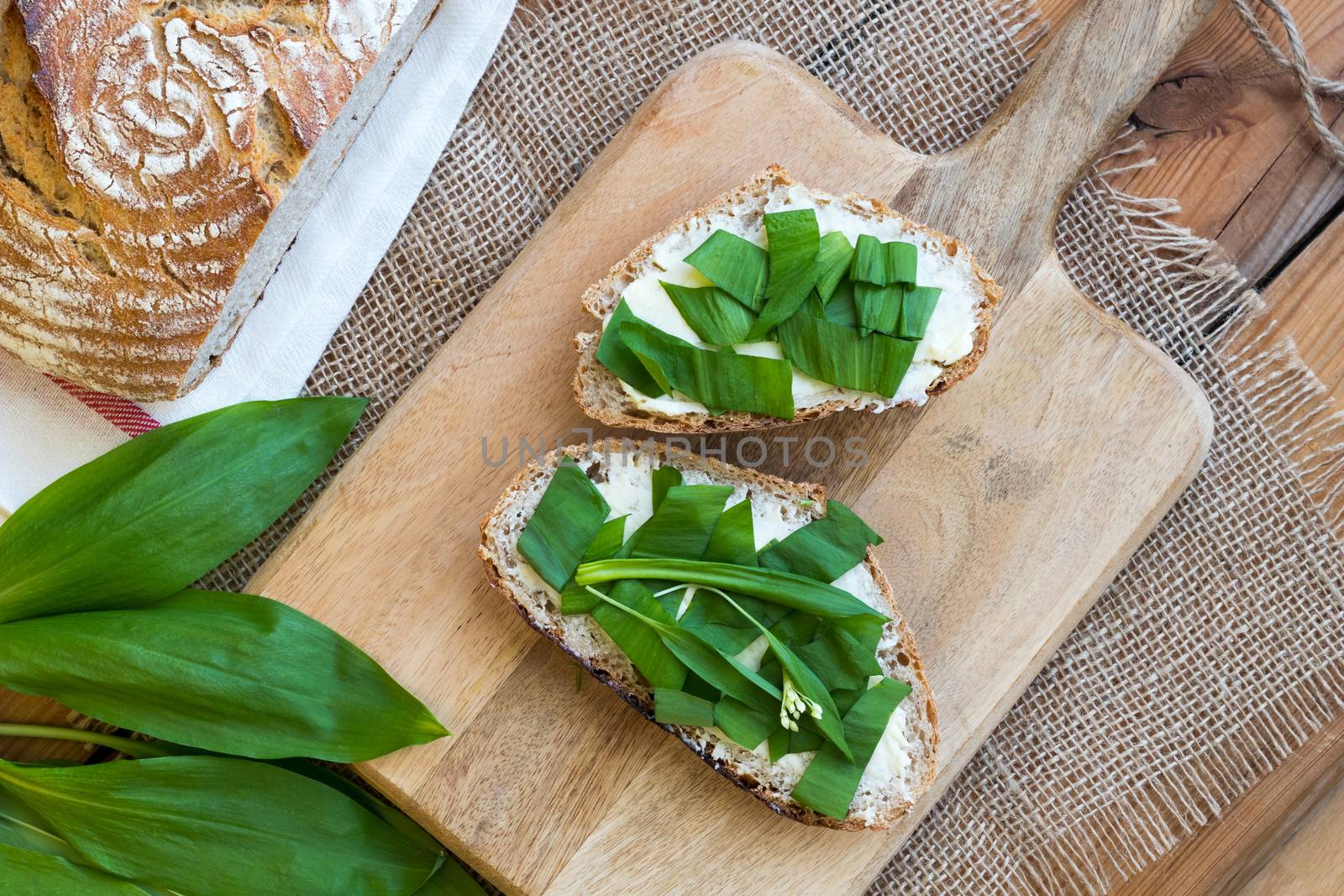Slices of sourdough bread with butter and wild garlic, top view