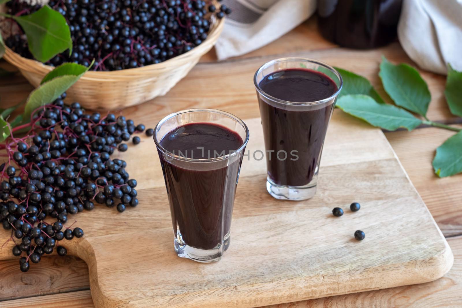 Two shots of black elder syrup with fresh elderberries