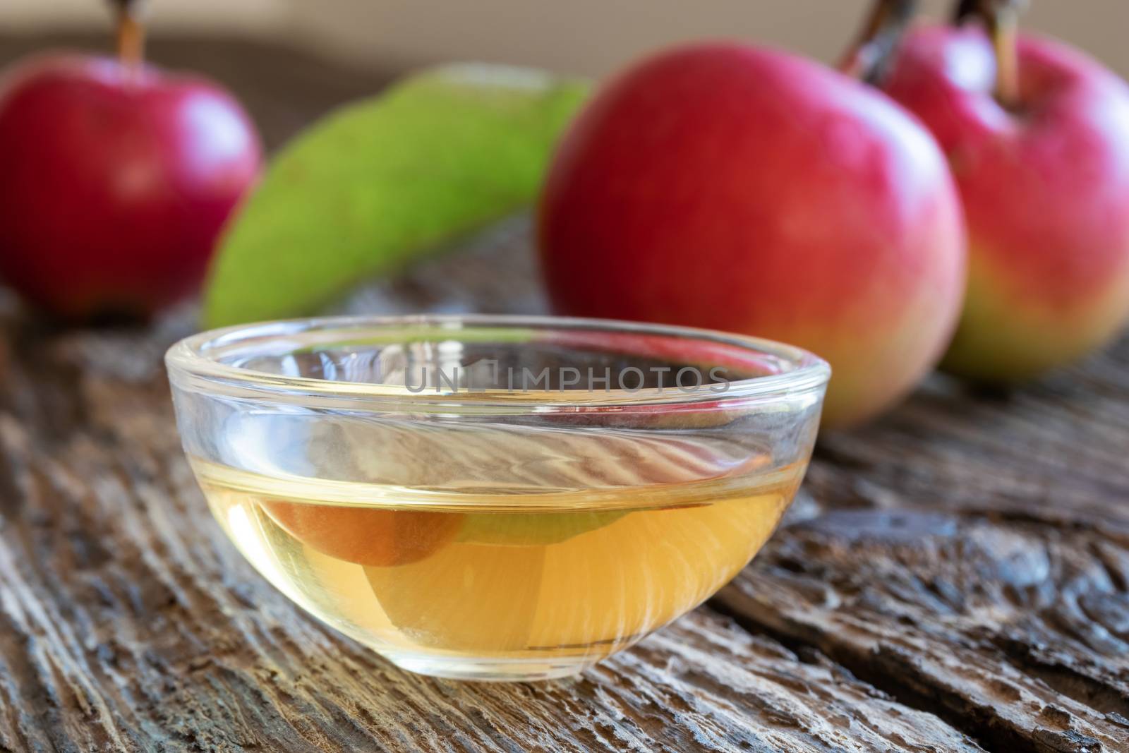 A bowl of apple cider vinegar on a wooden background