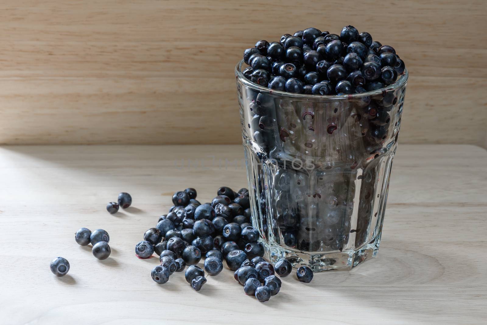 Blueberries in a glass with scattered berries. Good addition for your breakfast