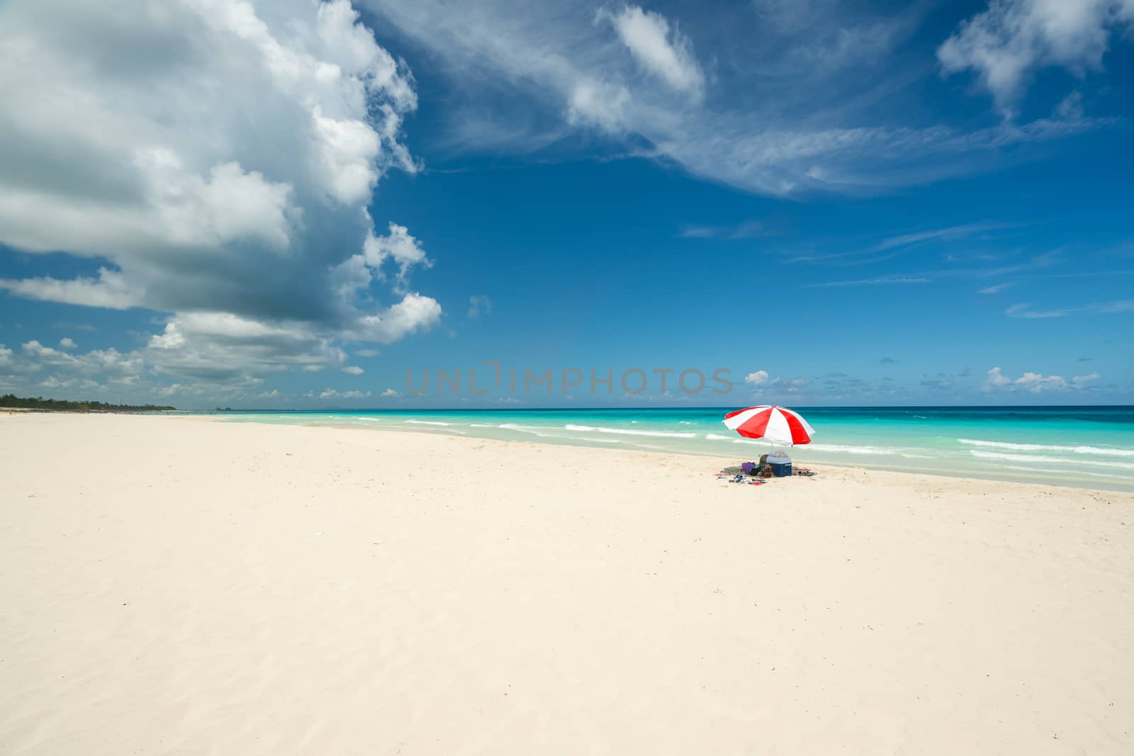 Beautiful beach of Varadero during a sunny day, fine white sand and turquoise and green Caribbean sea,on the right one red parasol,Cuba.concept  photo,copy space.