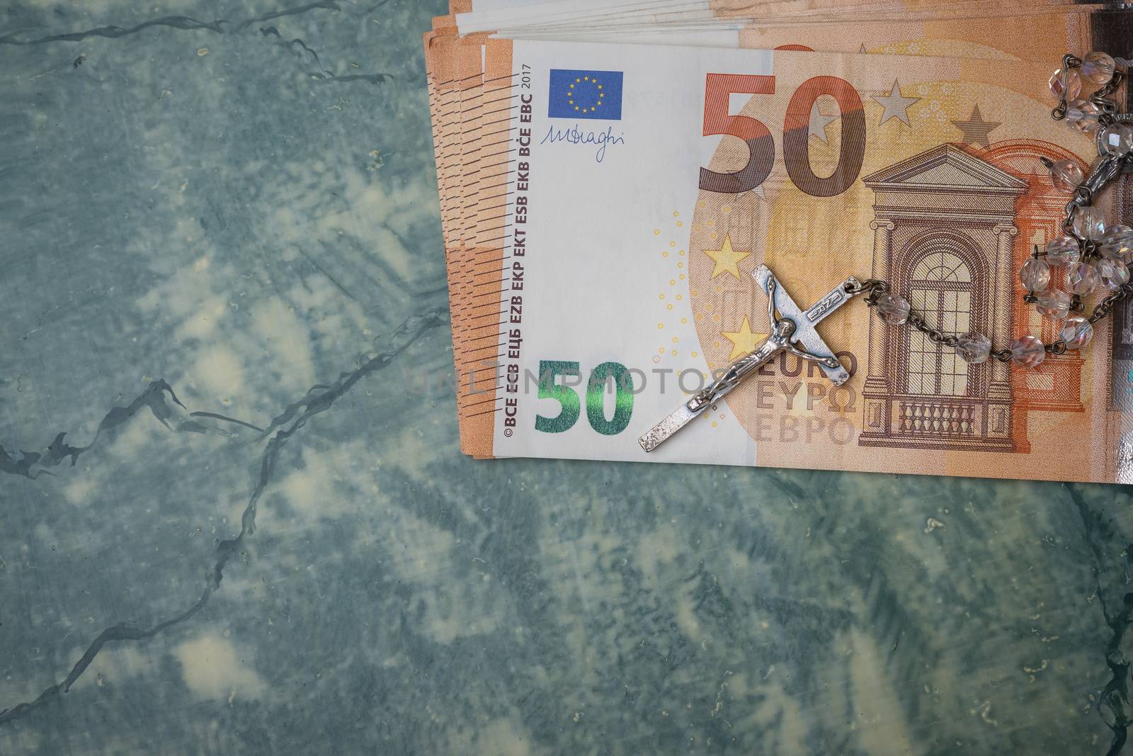 Silver  rosary and euro money on green table,concept photo.