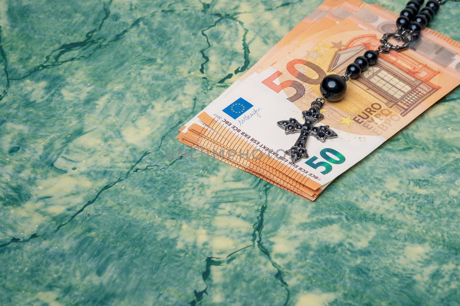 Black rosary and euro money on green table,concept photo.