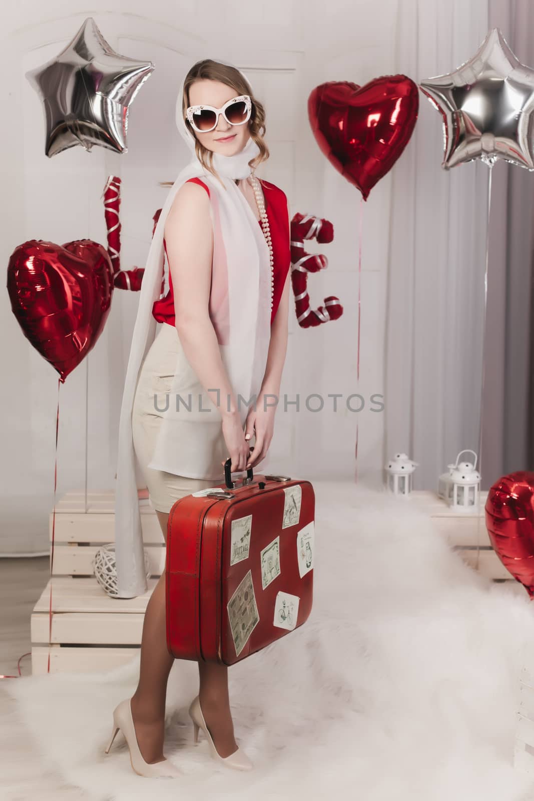 Retro girl posing in studio with suitcase by PhotoJovi