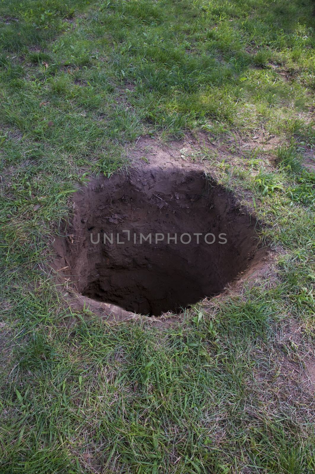 Deep dirt hole in ground or lawn