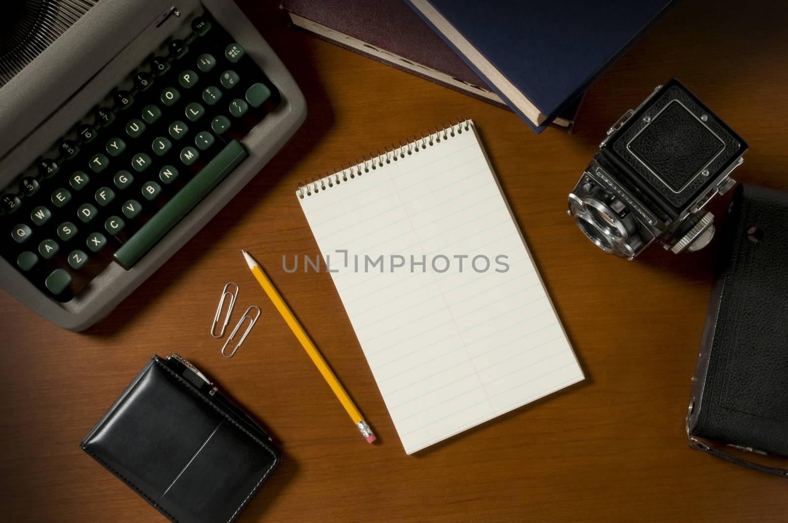 Blank steno notepad on a wooden desktop among vintage journalism props, including a typewriter and film camera