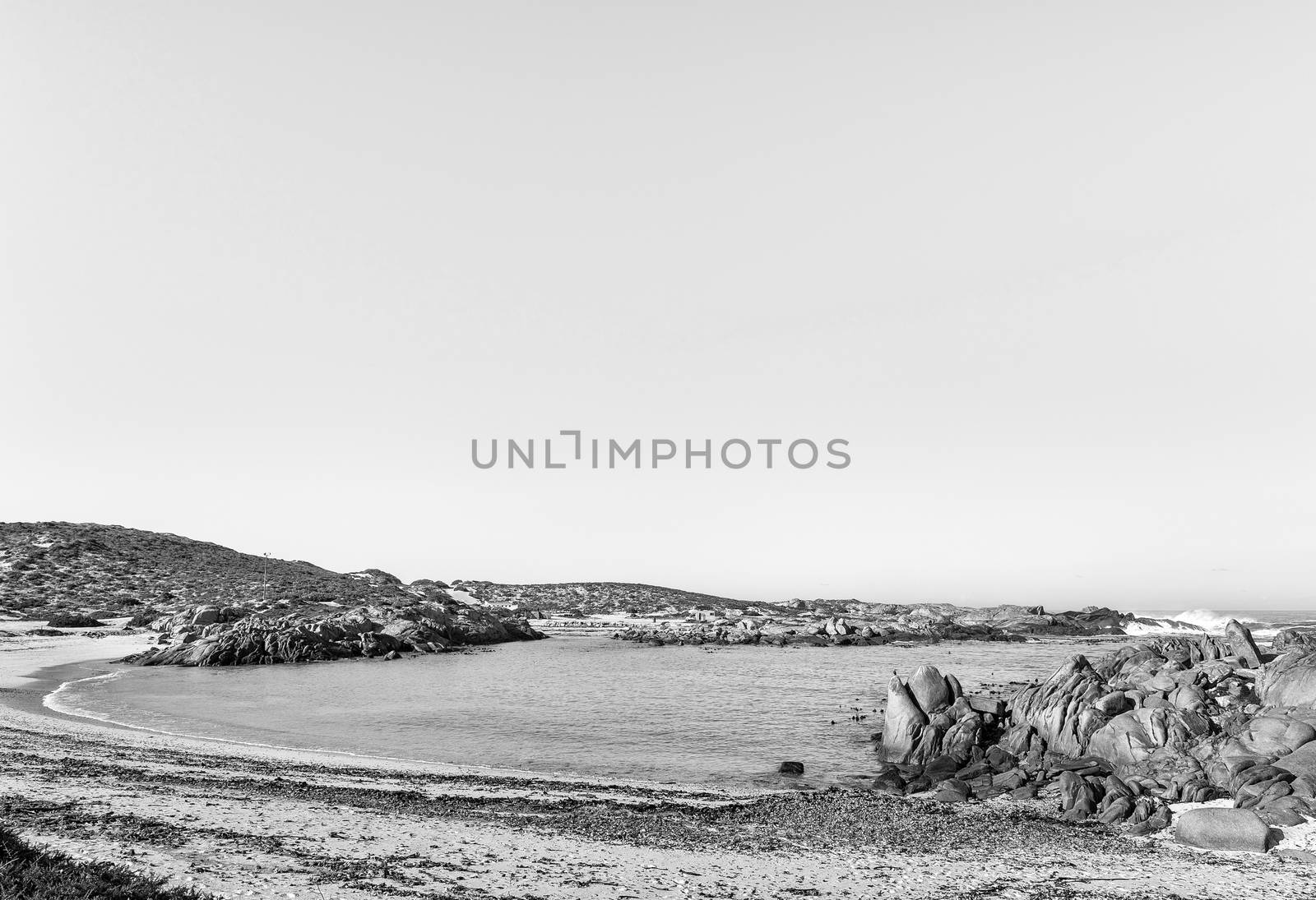 A view of Tietiesbaai Caravan Park in the Cape Columbine Nature Reserve near Paternoster. An ablution building and a motorhome are visible. Monochrome