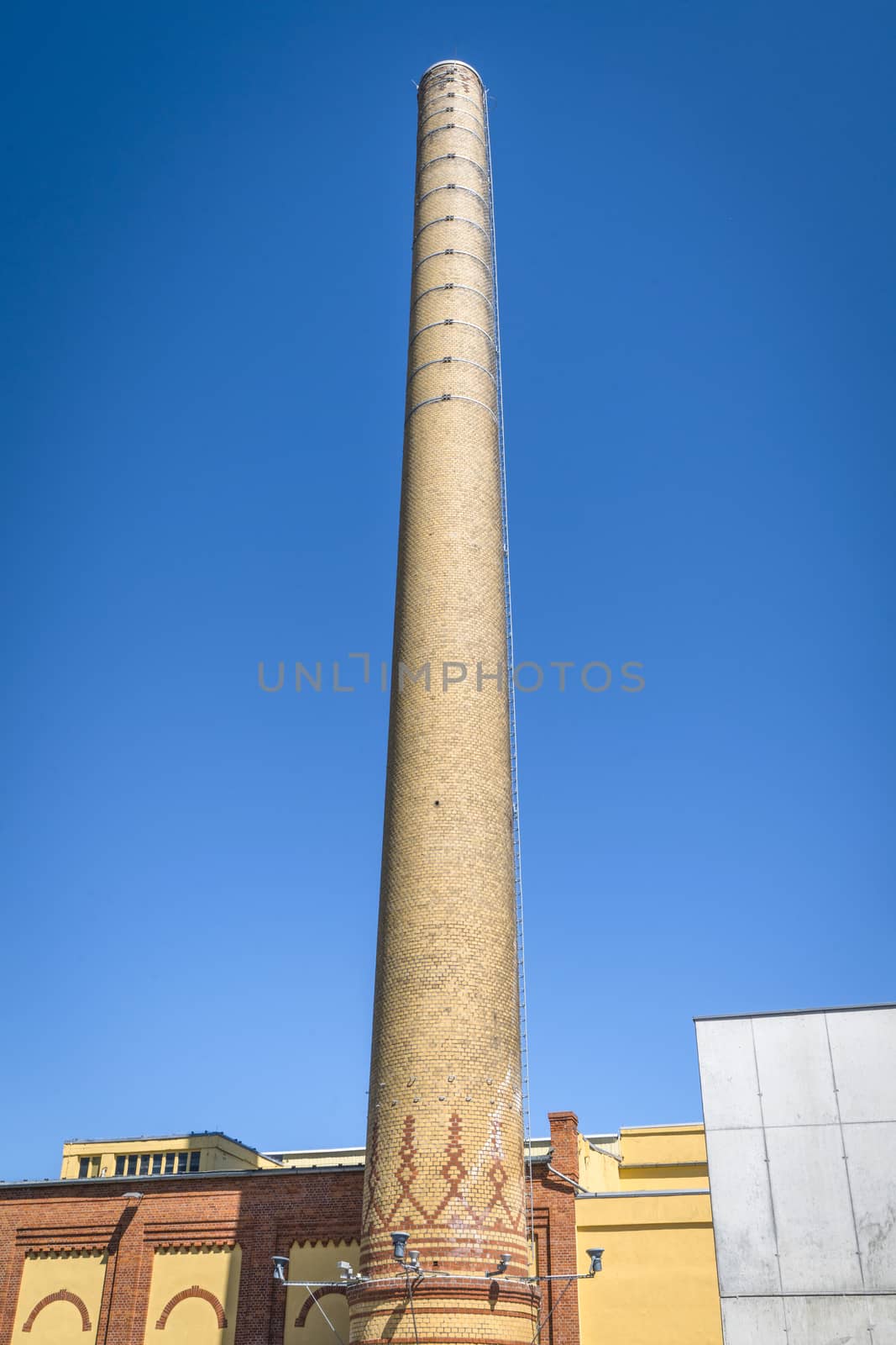 Tall chimney made of bricks on a factory by Sportactive