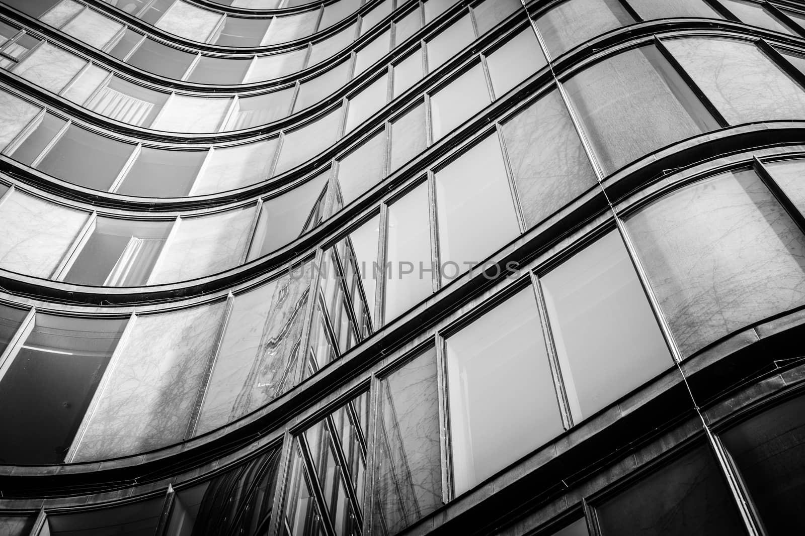 Curved building with shiny windows with reflections in black and white tone
