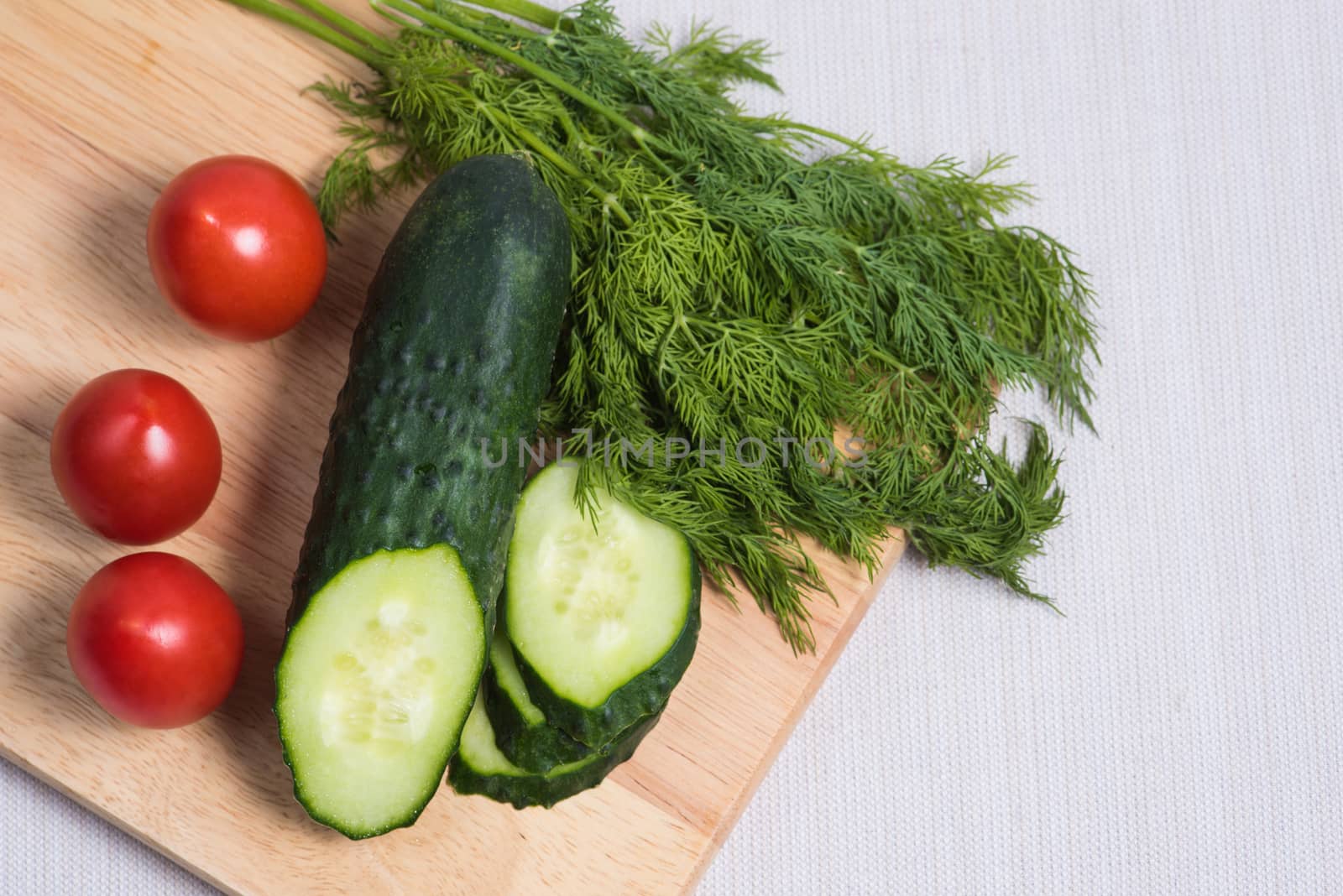 The concept of healthy eating with organic cucumber and cherry tomatoes on wooden table
