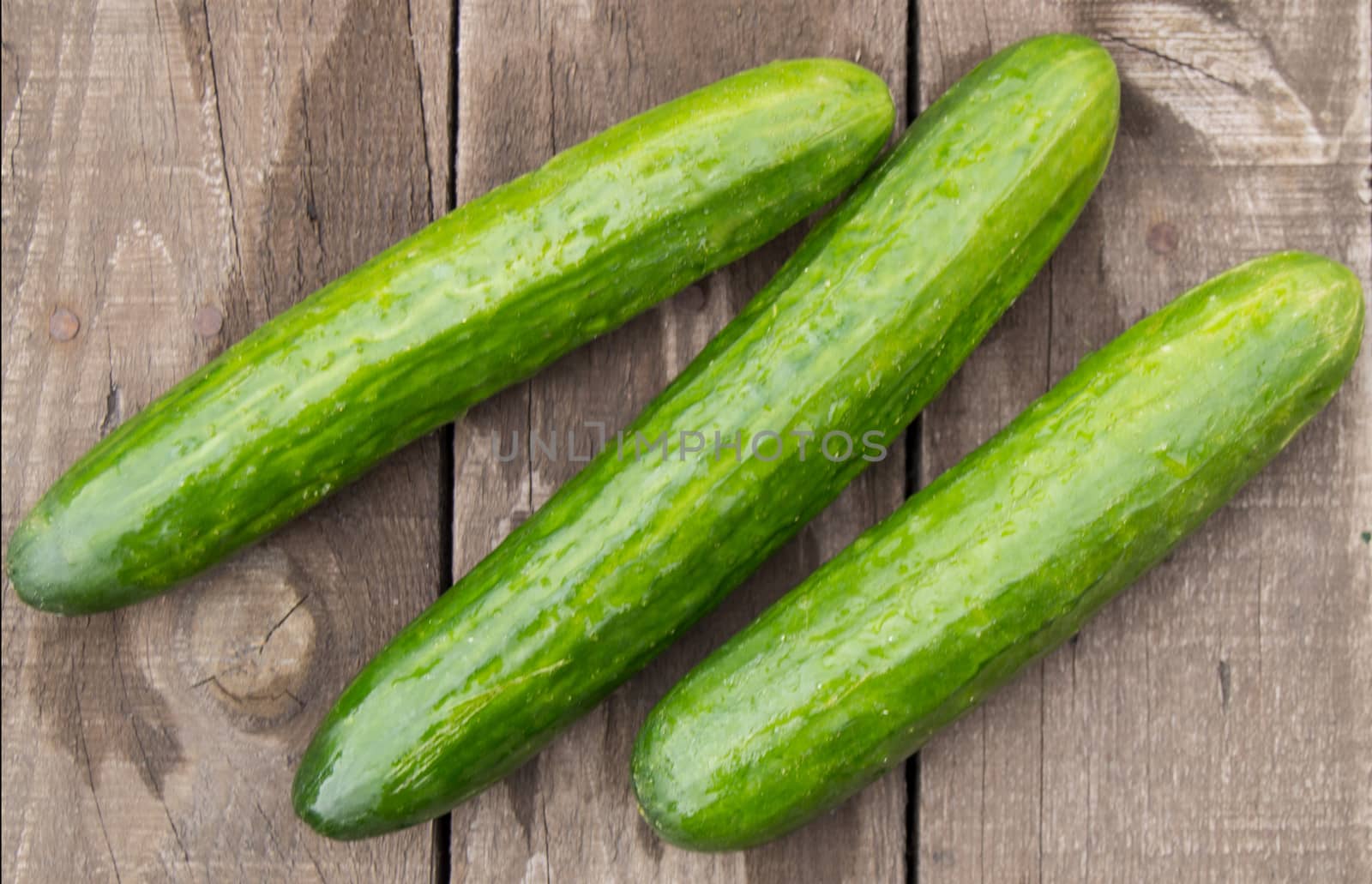 Fresh cucumbers on old wooden background, top view.