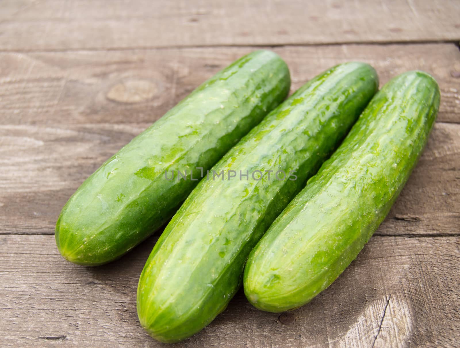Three fresh cucumber lying on an old wooden background by claire_lucia
