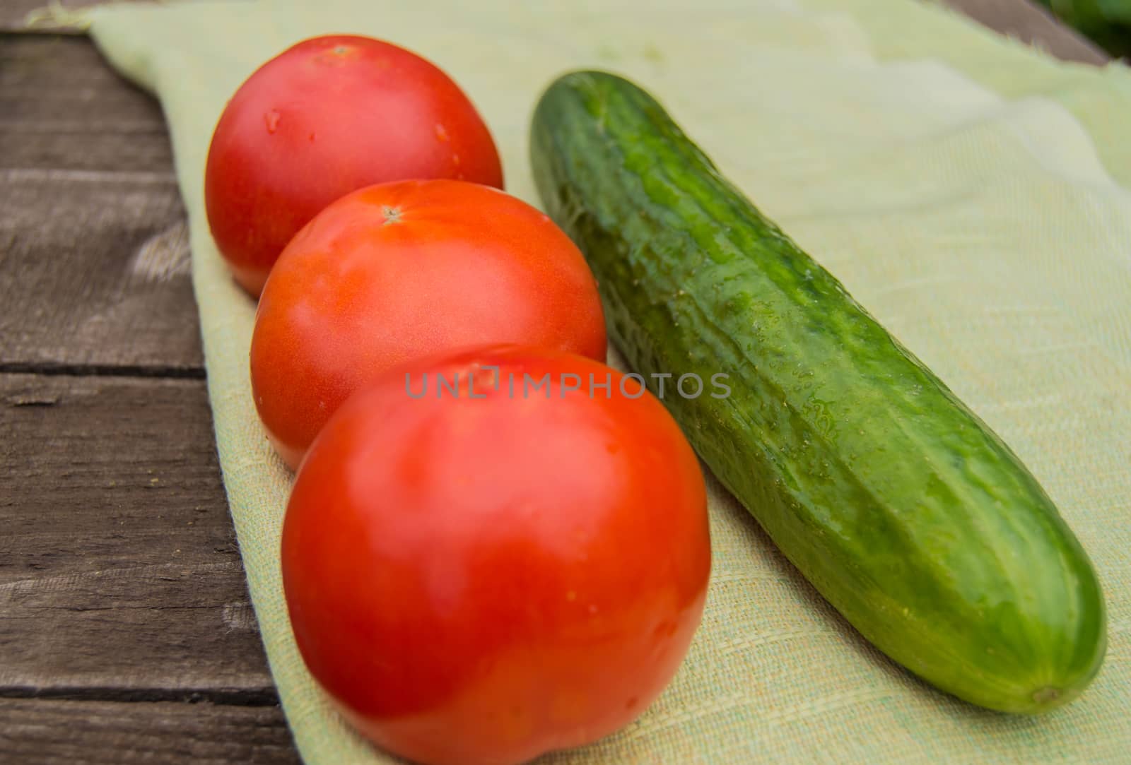 The concept of healthy eating with organic cucumber and cherry tomatoes on wooden table