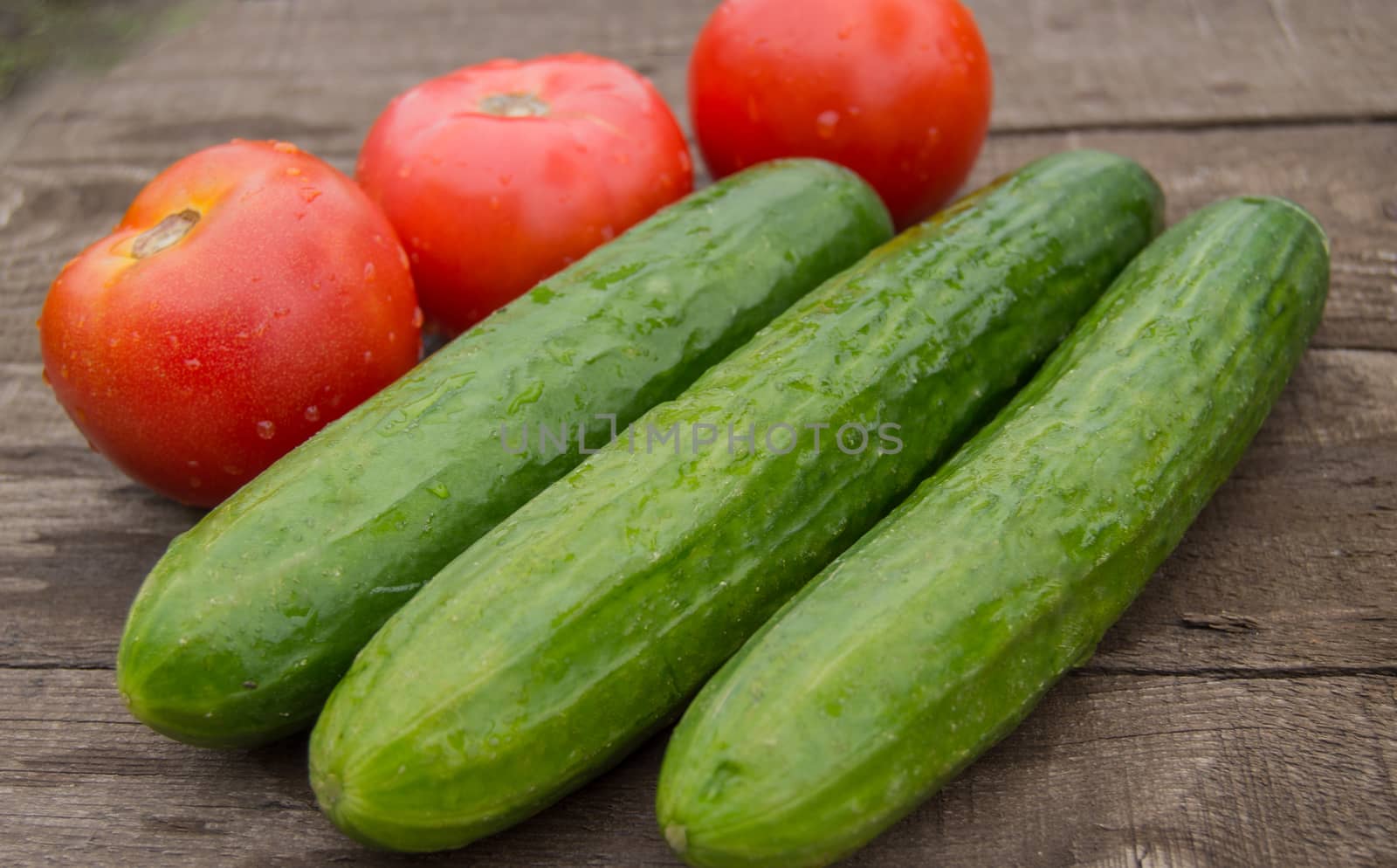 Concept of healthy eating with organic cucumber tomatoes, wooden background.