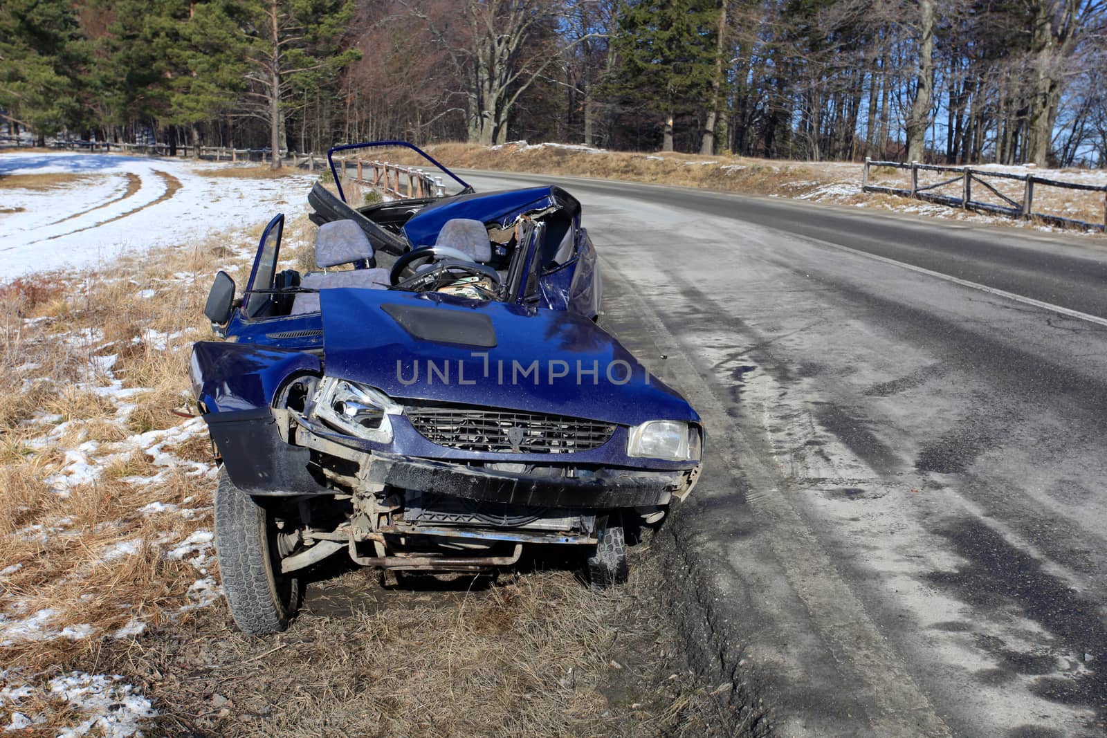 Front of blue car damaged by crash accident on side of the road